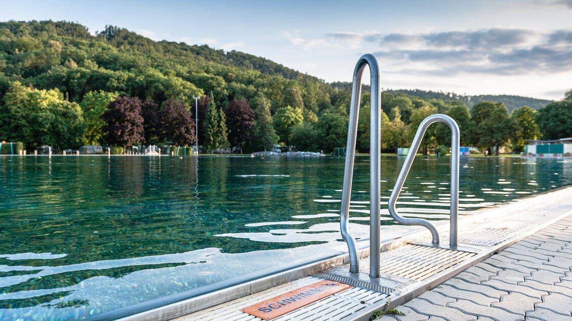 <p>Blick auf das Bad Straßgang in Graz mit Wasserzugang und Waldkulisse</p> | © Holding Graz - Joel Kernasenko