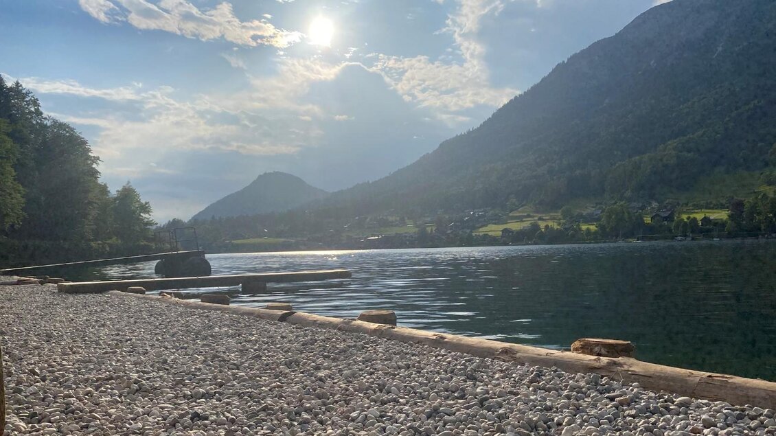 <p>Der Seezugang im Freibad auf der Au in Grundlsee mit Steg. Die Sonne scheint und reflektiert auf dem Wasser.</p> | © Bettina Scheck