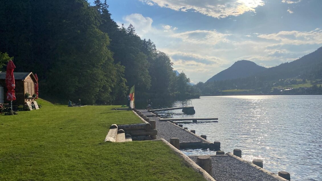 <p>Der ruhige Grundlsee umgeben der grünen Liegewiese mit dem Seezugang und den Bergen des Ausseerlandes. Der Grundlsee glitzert bei Sonnenschein.</p> | © Bettina Scheck