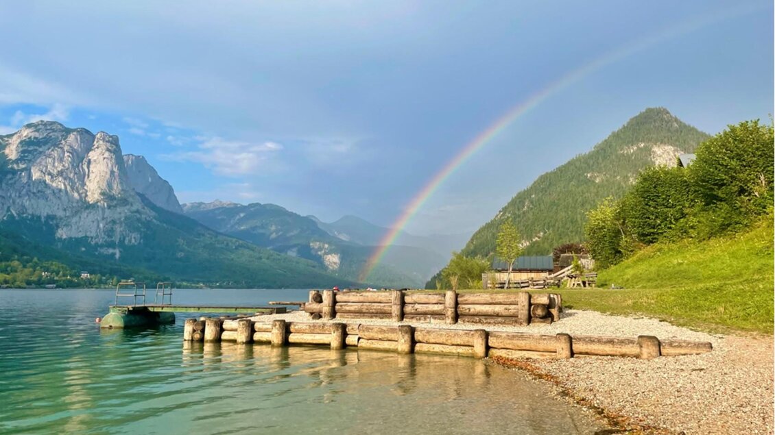 Das Freibad auf der Au am Grundlsee – kristallklares Wasser, der imposante Backenstein – der Hausberg von Grundlsee – und ein leuchtender Regenbogen an einem schönen Sommertag. | © Bettina Scheck
