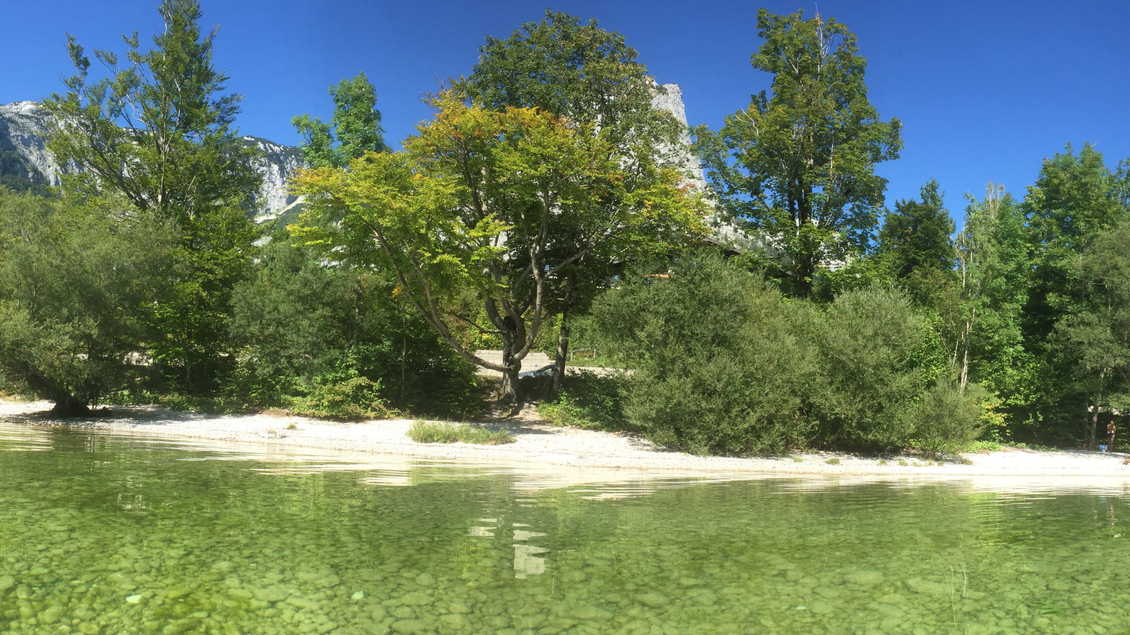 Ein klarer, grüner See umgeben von saftigen Bäumen und Felsen. Die Uferseite mit feinem Kies strahlt eine ruhige Atmosphäre aus. | © Tourismusverband Ausseerland