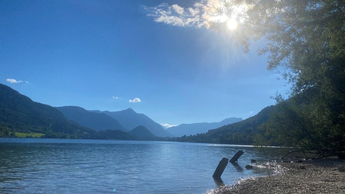 Ein ruhiger See, umgeben von Bergen und Bäumen. Die Sonne strahlt über dem Wasser und schafft eine friedliche Atmosphäre. | © Tousimusverband Ausseerland
