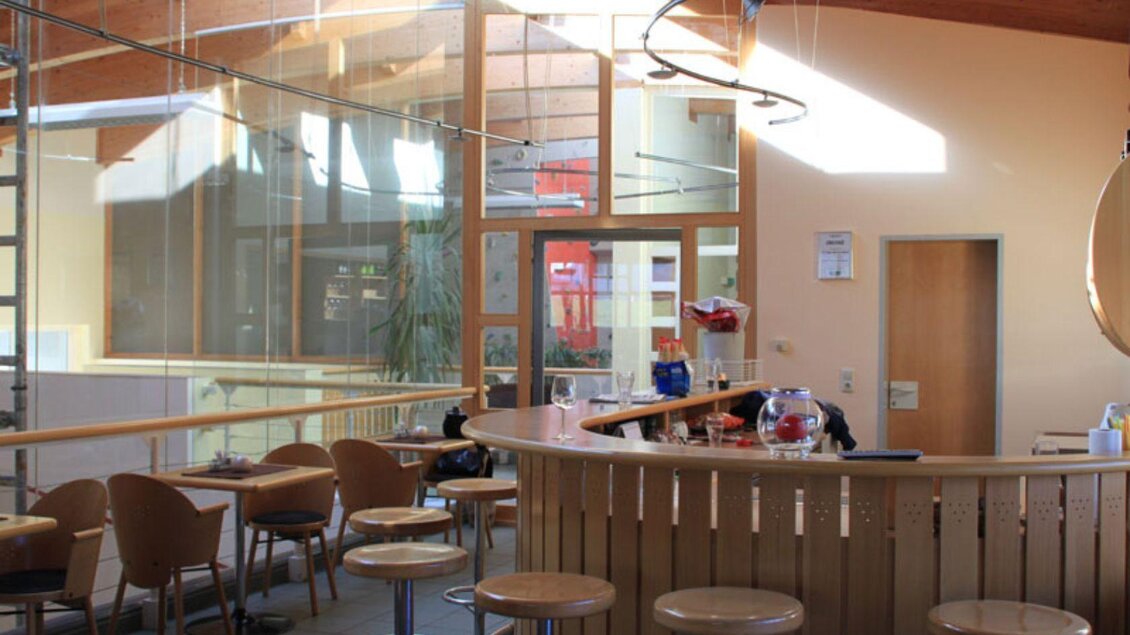 Das Sportstüberl mit der MiXed Bar in Bad Mitterndorf mit hellen Holzelementen und großen Fenstern. Die Einrichtung ist minimalistisch mit einer Bar und Sitzgelegenheiten gestaltet. | © Otwin Sparer