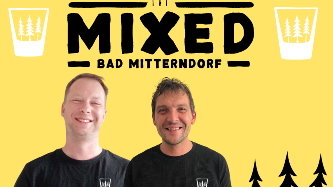 Das Logo der MiXed Bar in Bad Mitterndorf mit den Besitzern, welche vor einem gelben Hintergrund mit dem Schriftzug „MIXED BAD MITTERNDORF“ stehen. Sie tragen schwarze T-Shirts und lächeln freundlich. | © Mixed Team