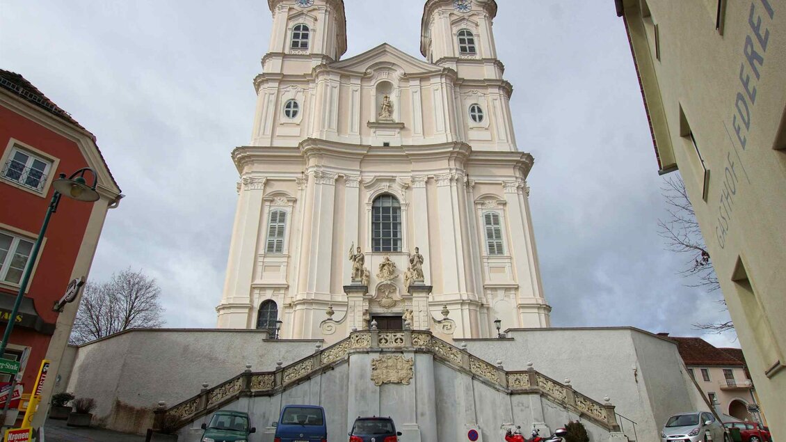 Eine beeindruckende Kirche mit zwei Türmen und einer prächtigen Fassade. Die Kirche steht auf einer Treppe in einer städtischen Umgebung. | © Tourismusverband Oststeiermark