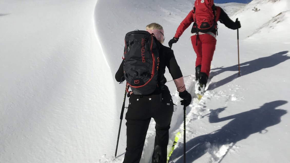 Zwei Personen steigen einen verschneiten Hang hinauf. Der Himmel ist blau und der Schnee glänzt in der Sonne. | © Bergführer Dachstein – Hans Prugger