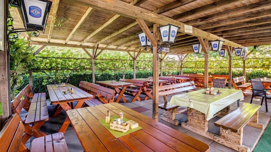 <p>Ein einladender Biergarten mit rustikalen Holztischen und Bänken unter einem schattigen Dach. Die Umgebung ist grün und freundlich gestaltet. Bergschenke Schlögl in Kirchberg an der Raab</p> | © Andreas Schlögl