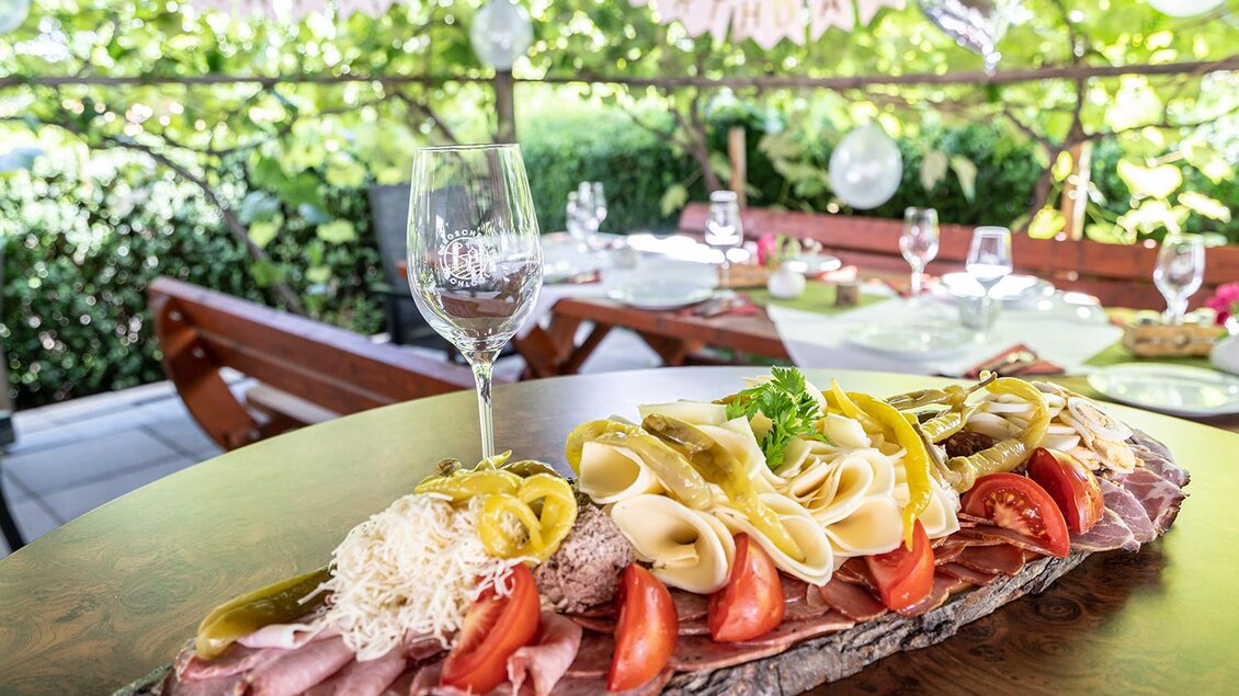 <p>Eine festliche Platte mit verschiedenen Wurst- und Käsesorten, garniert mit Gemüse. Im Hintergrund sieht man eine gedeckte Tafel und eine "Happy Birthday"-Dekoration. Bergschenke Schlögl in Kirchberg an der Raab</p> | © Andreas Schlögl