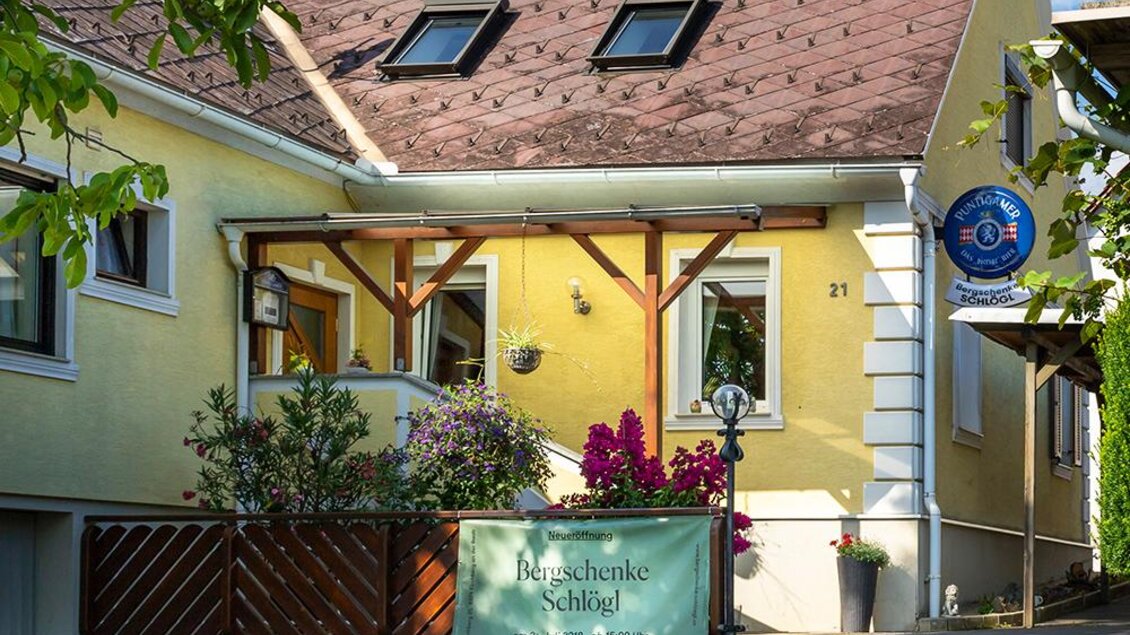 <p>Ein charmantes Haus mit einem hellen gelben Anstrich und einem schrägen Dach. Draußen befinden sich Pflanzen und ein Schild mit der Aufschrift "Bergschänke Schlegl". Bergschenke Schlögl in Kirchberg an der Raab</p> | © Andreas Schlögl