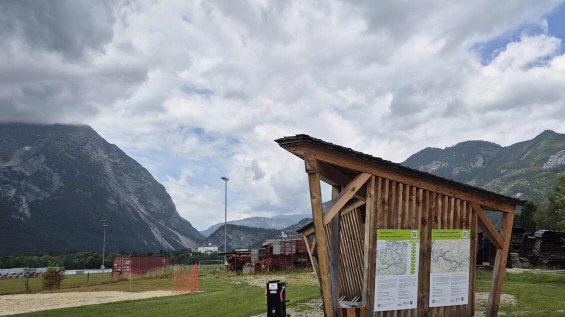 Eine Holzunterkunft steht auf einer Wiese mit Bergen im Hintergrund. Der Himmel ist bewölkt und es ist eine ruhige Landschaft zu sehen. | © TVB Schladming-Dachstein