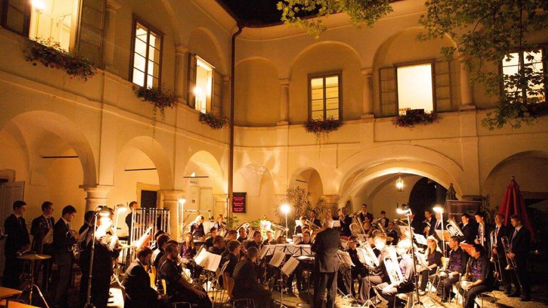 Ein Orchester spielt in einem schön beleuchteten Innenhof. Die Atmosphäre ist festlich und einladend. | © Retzhof