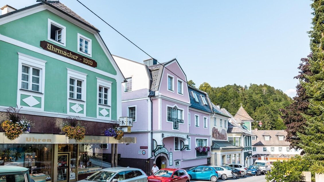 Eine malerische Straße mit bunten Häusern und Geschäften. Parkende Autos und Bäume im Hintergrund verleihen der Szene einen charmanten, kleinen Stadtcharakter. | © Thomas Sattler