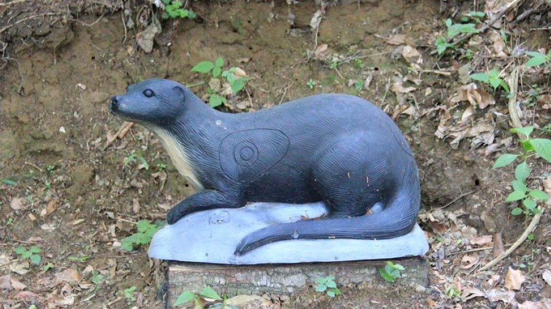 Eine Statue eines Otters, die auf einem Holzblock steht. Der Hintergrund besteht aus Erde und Pflanzen. | © Ulrike Elsnegg