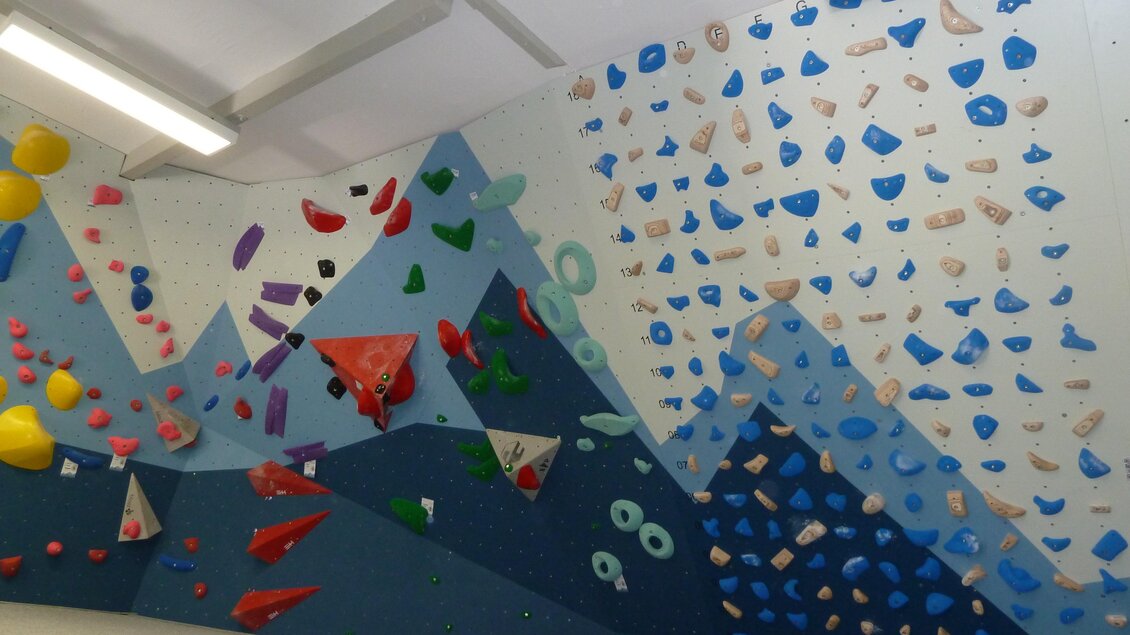 Innenansicht der Boulderhalle des Österreichischen Alpenvereins Voitsberg mit farbigen Klettergriffen an geneigten Wänden

 | © Hans Fink