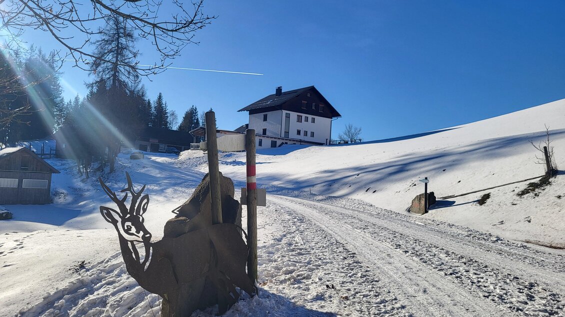 Eine herrliche Schneelandschaft im Sonnenschein mit einem Haus und einem Wegweiser. | © Andrea Stelzer