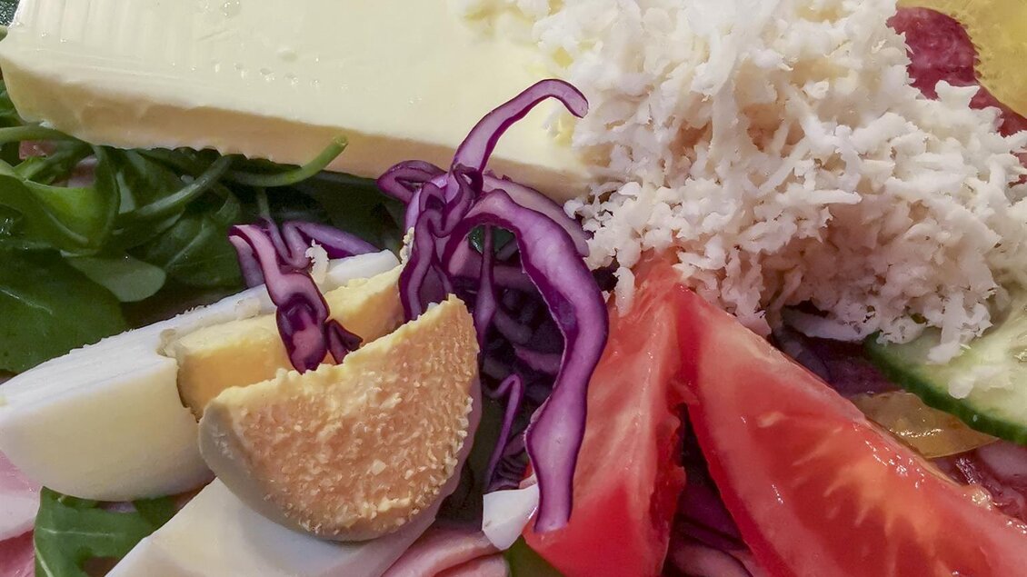 Ein bunter Teller mit verschiedenen Wurst- und Käsesorten, frischem Gemüse und Obst. Darunter befinden sich Salat, Tomaten, Äpfel und Rotkohl. | © Stefan Gründl | Weingut Gründl