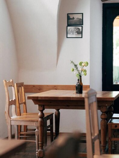 Ein gemütliches Restaurant mit einem Holztisch und Stühlen. Auf dem Tisch steht eine Vase mit frischen Blumen. | © Heldentheater