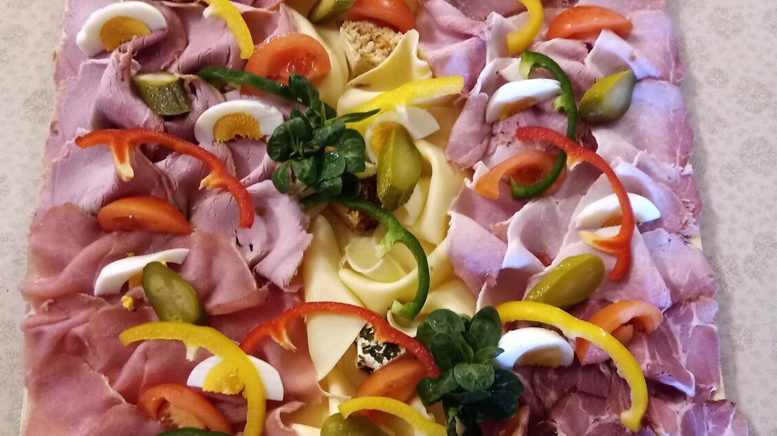 Ein schön angerichteter Aufschnittteller mit verschiedenen Wurst- und Käsesorten. Bunte Paprikastreifen und Gurkenröllchen sorgen für eine ansprechende Präsentation. | © Buschenschank Heschl