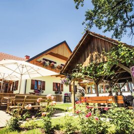 Ein einladendes Gasthaus mit einer schönen Terrasse. Blumenschmuck und Sonnenschirme schaffen eine gemütliche Atmosphäre im Freien. | © Schilcherland Steiermark