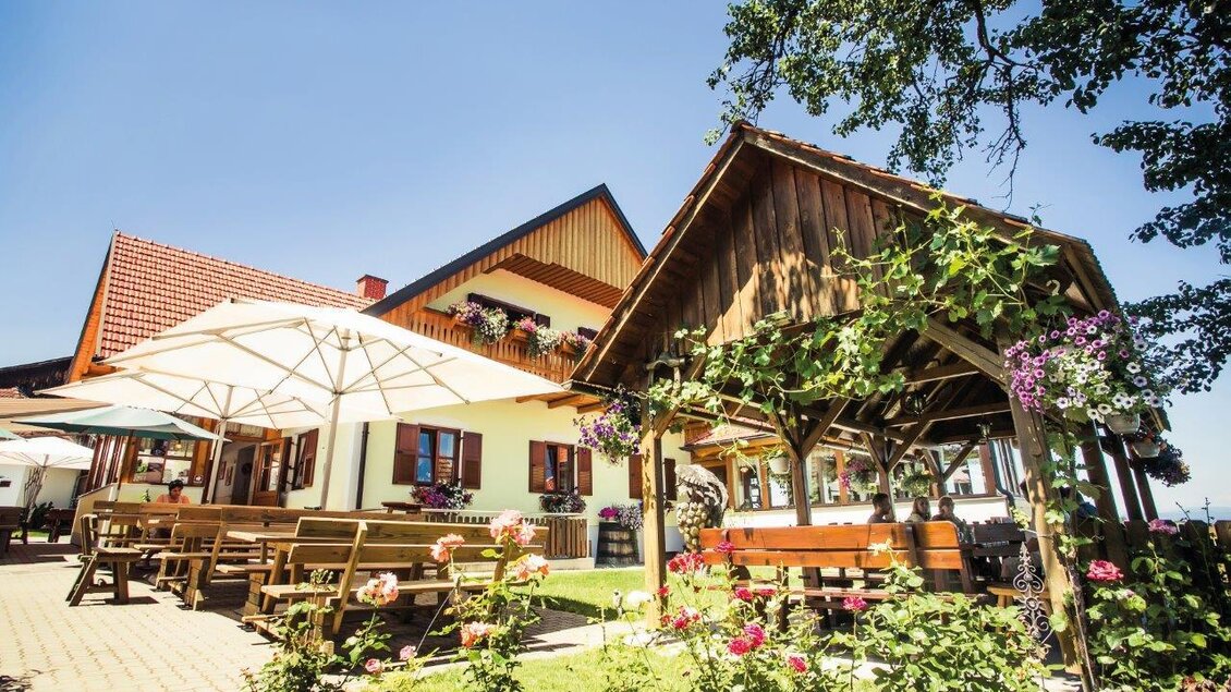 Ein einladendes Gasthaus mit einer schönen Terrasse. Blumenschmuck und Sonnenschirme schaffen eine gemütliche Atmosphäre im Freien. | © Schilcherland Steiermark