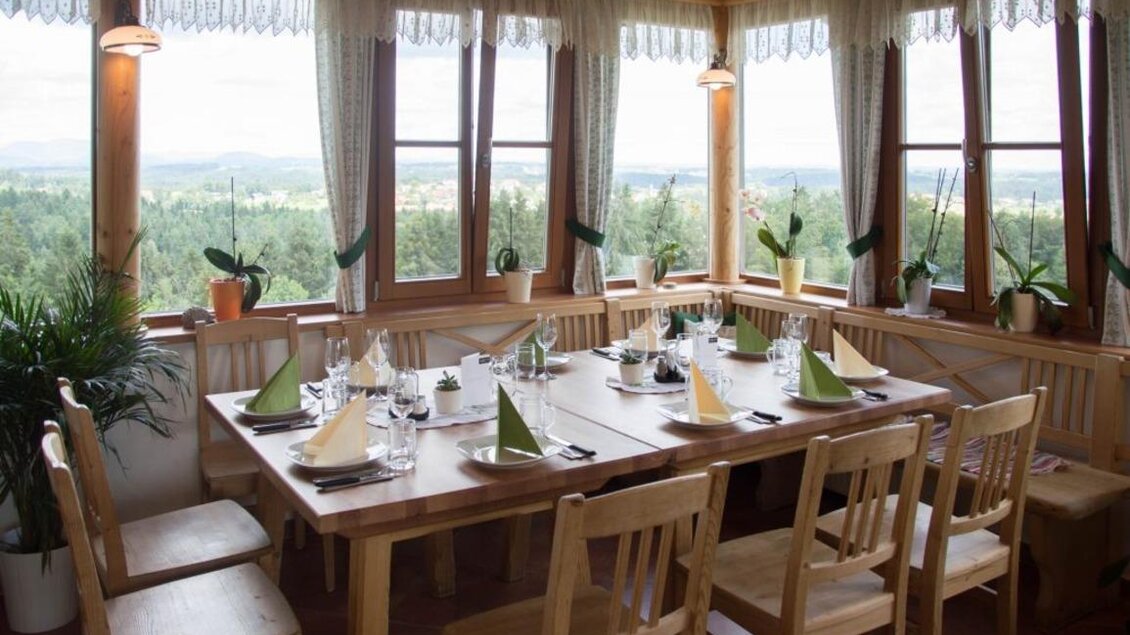 Ein einladender Speisesaal mit großen Fenstern und Aussicht auf die Natur. Der Tisch ist elegant gedeckt mit Tischtüchern und Dekorationen. | © Schilcherland Steiermark