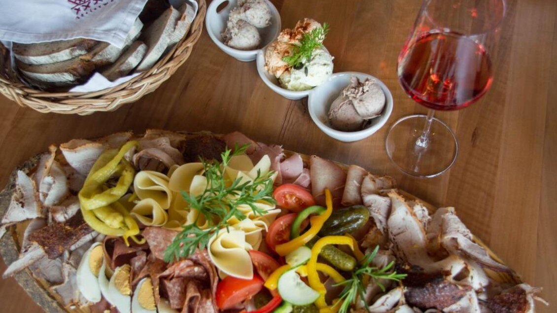 Ein reichhaltiges Wurst- und Käsebrett mit buntem Gemüse und Gewürzgurken. Dazu gibt es ein Glas Roséwein und kleine Schalen mit Eis. | © Schilcherland Steiermark