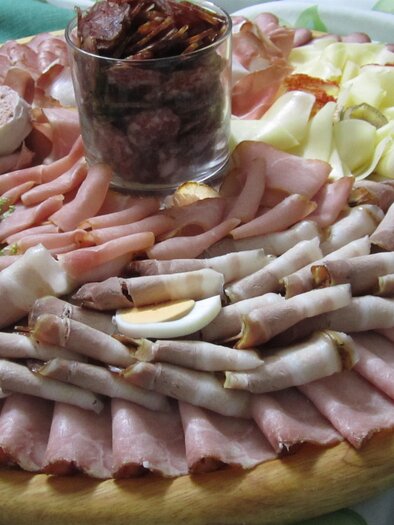 Ein reichhaltiges Käse- und Wurstbrett mit verschiedenen Aufschnittsorten, Ei und Salat. In der Mitte befindet sich ein Glas mit Trockenfrüchten. | © Weingut Holler