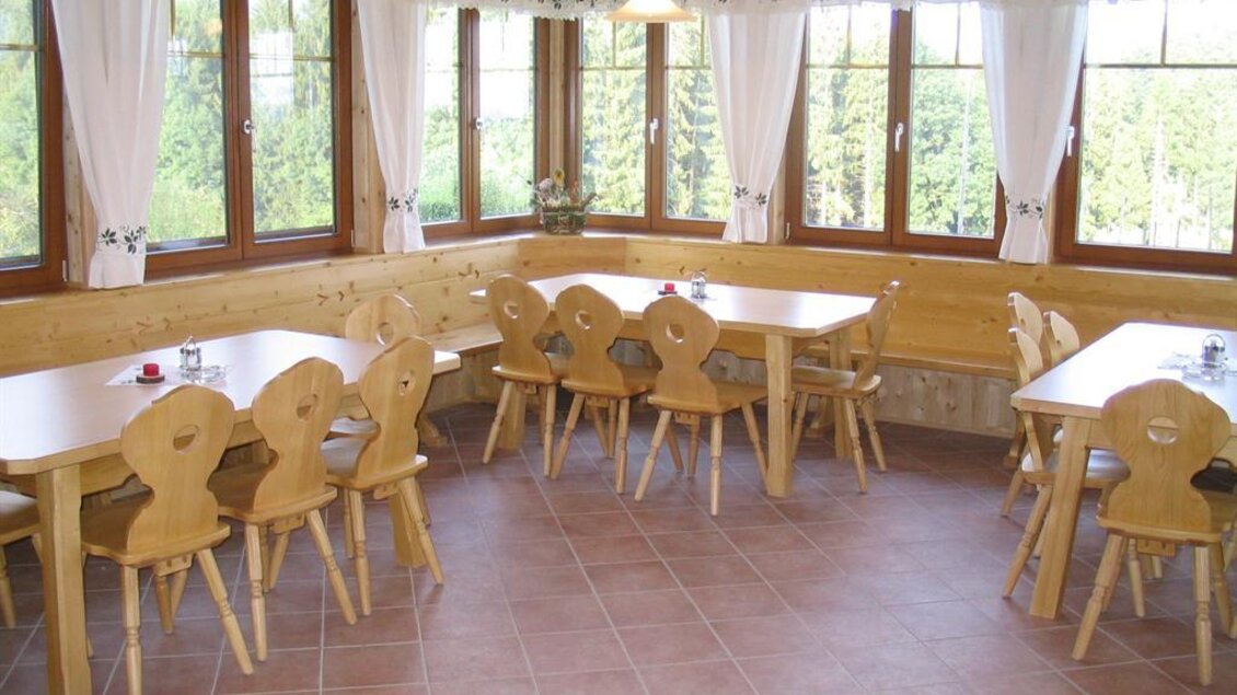 Helle Gaststube mit Holzmöbeln und großen Fenstern im Buschenschank Schachner in Köflach. | © Buschenschank Schachner