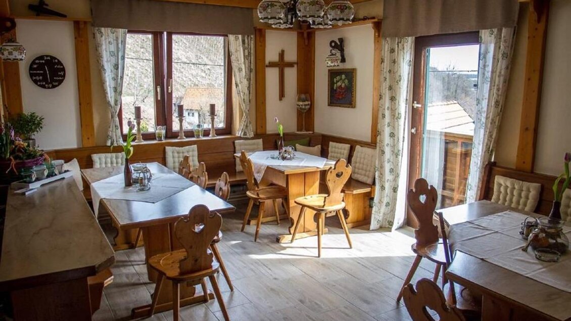 Ein gemütlicher Speisesaal mit Holzmöbeln und hellen Fenstern. Der Raum ist einladend und freundlich gestaltet. | © Buschenschank Stoff