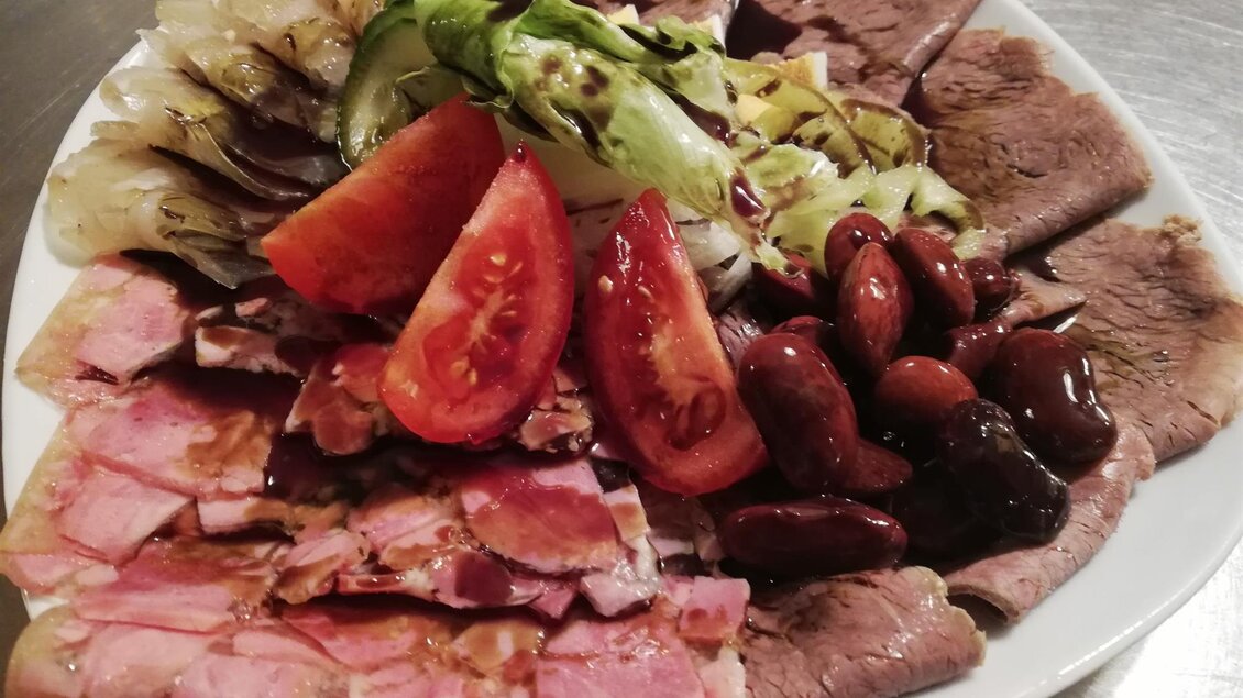 Ein reichhaltiger Teller mit verschiedenen Fleischsorten, frischem Gemüse und Tomaten. Eine köstliche Kombination aus verschiedenen Aromen und Texturen. | © Buschenschank Stoff