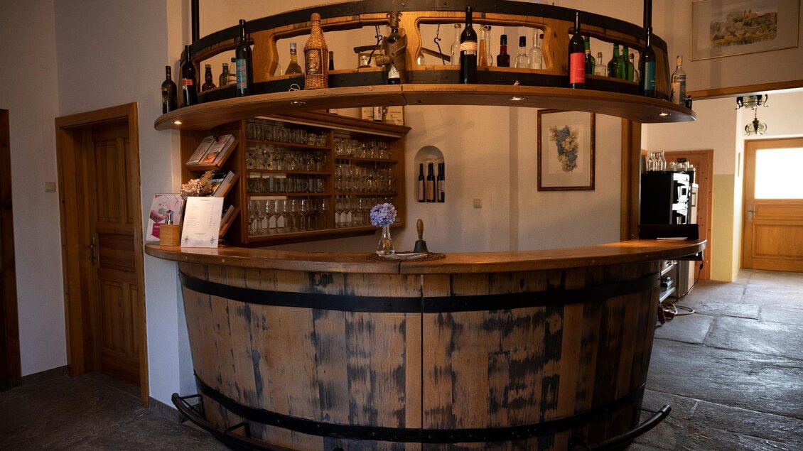 Eine rustikale Bar aus Holz mit Weinflaschen und Gläsern. Der Raum wirkt einladend und gemütlich. | © TV Südsteiermark - Dominik Feibel