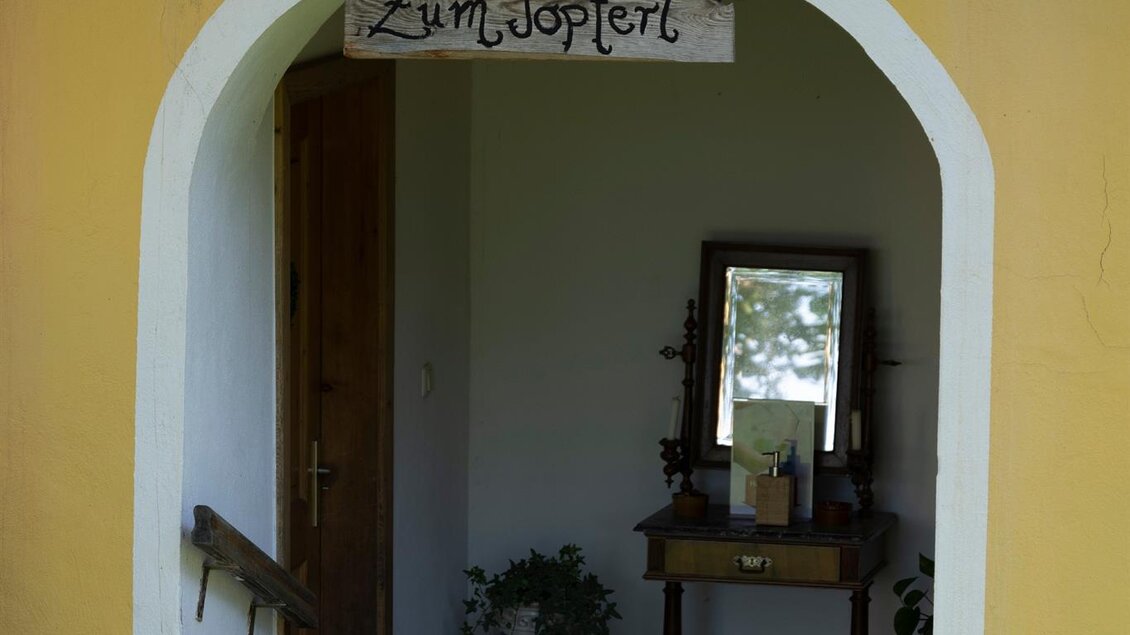 Ein einladender Eingangsbereich mit einem Schild "Zum Topfler". Der Raum hat eine warme Atmosphäre und zeigt eine freundliche Einrichtung. | © TV Südsteiermark - Dominik Feibel