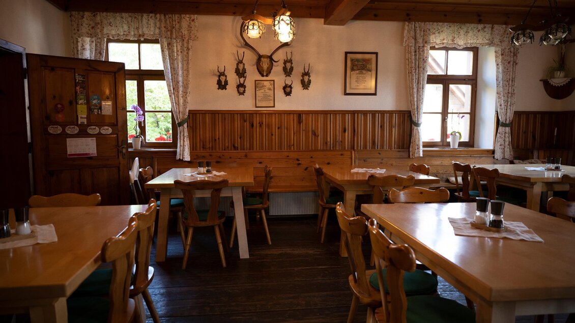 Ein rustikales Restaurant mit Holztischen und -stühlen. An den Wänden hängen Jagdtrophäen und es gibt große Fenster mit Vorhängen. | © TV Südsteiermark - Dominik Feibel