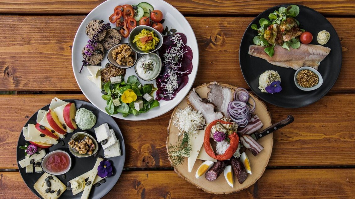 Ein stilvolles Arrangement von verschiedenen Gerichten auf mehreren Tellern. Die Speisen umfassen frische Salate, Käse, Gemüse und delikate Häppchen. | © Andrea Bayr