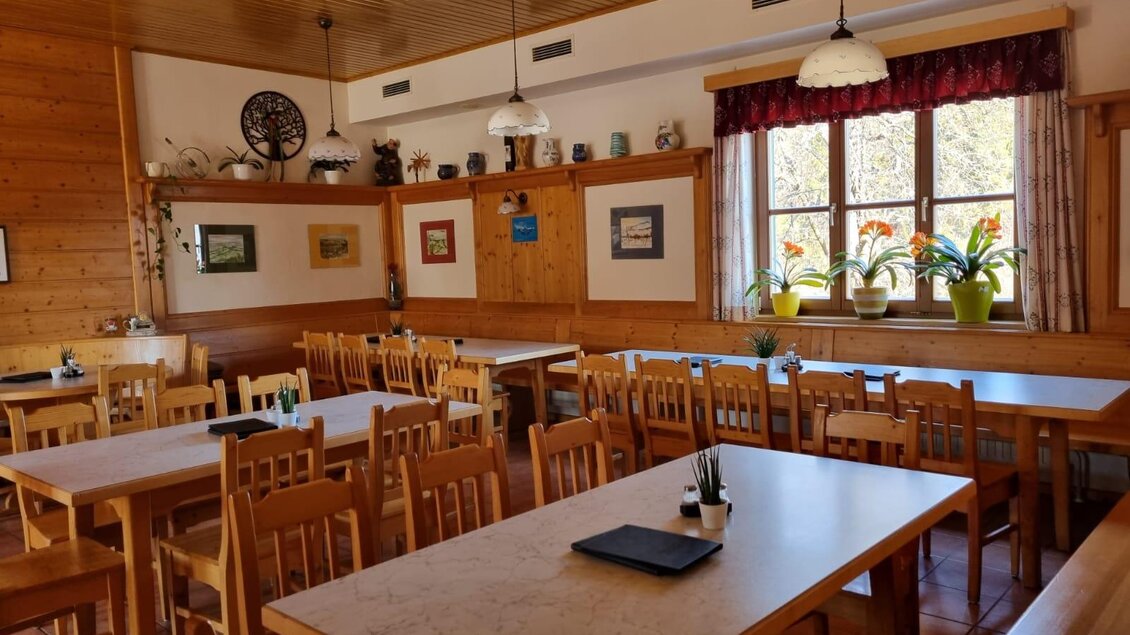 Ein gemütliches Restaurant mit Holzwänden und großen Fenstern. Die Tische sind ordentlich eingedeckt und es gibt viele Pflanzen auf der Fensterbank. | © Schweighofer