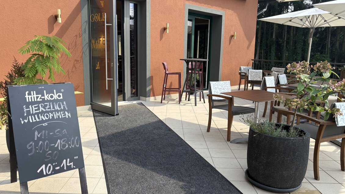 Terrasse des Café Marie in Eggersdorf mit Sitzplätzen, Sonnenschirmen und geöffnetem Eingang. | © Jula Zangger