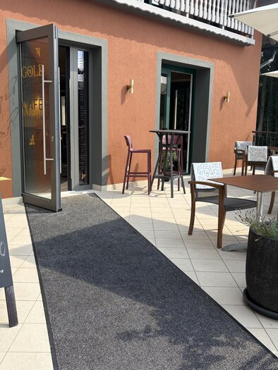 Terrasse des Café Marie in Eggersdorf mit Sitzplätzen, Sonnenschirmen und geöffnetem Eingang. | © Jula Zangger