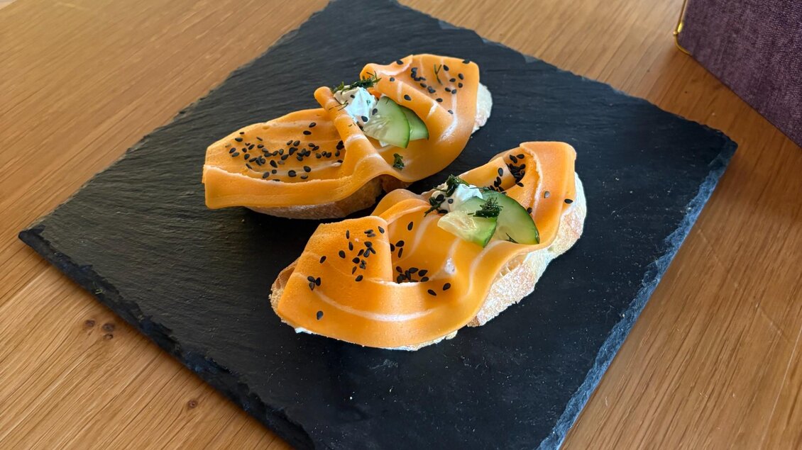 Zwei Lachsbrötchen mit Gurke, Creme, Kräutern und schwarzem Sesam auf einer Schieferplatte im Café Marie in Eggersdorf. | © Harry Schiffer Photodesign