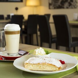 Symbolbild Kaffeegetränk, Wasser und eine süße Mehlspeise auf einem gedeckten Tisch.  | © TV Region Graz-Rene Vidalli
