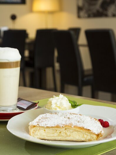 Symbolbild Kaffeegetränk, Wasser und eine süße Mehlspeise auf einem gedeckten Tisch.  | © TV Region Graz-Rene Vidalli