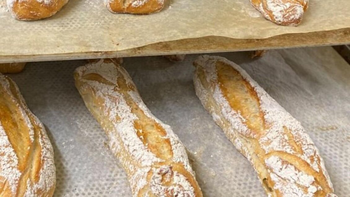 Frische Baguettes mit einer goldenen Kruste, bestäubt mit Mehl, liegen auf einem Backblech. Sie sehen appetitlich und knusprig aus. | © Bäckerei-Konditorei Hubmann Josef GmbH