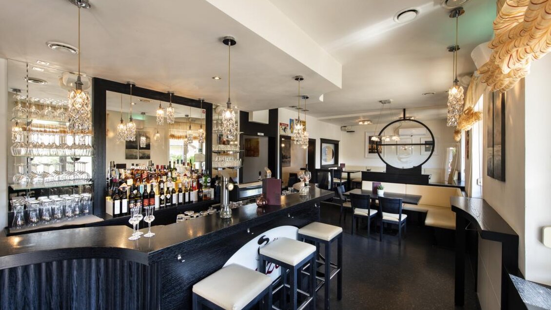 Ein modernes Restaurant mit einer eleganten Bar und stilvollen Stühlen. Die Atmosphäre ist hell und einladend, ideal für gesellige Treffen. | © Bachner Hotel BetriebsgesmbH