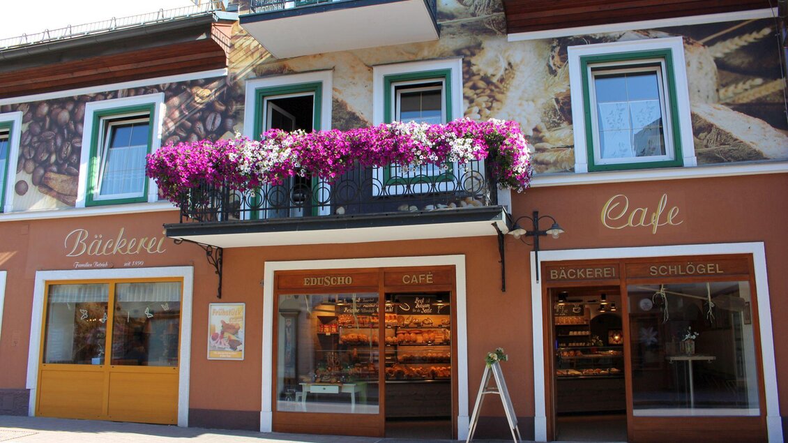 Ein einladendes Café mit einer Bäckerei im Erdgeschoss. Blühende Pflanzen schmücken den Balkon über der Eingangstür. | © TVB Ausseerland - Salzkammergut_Viola Lechner