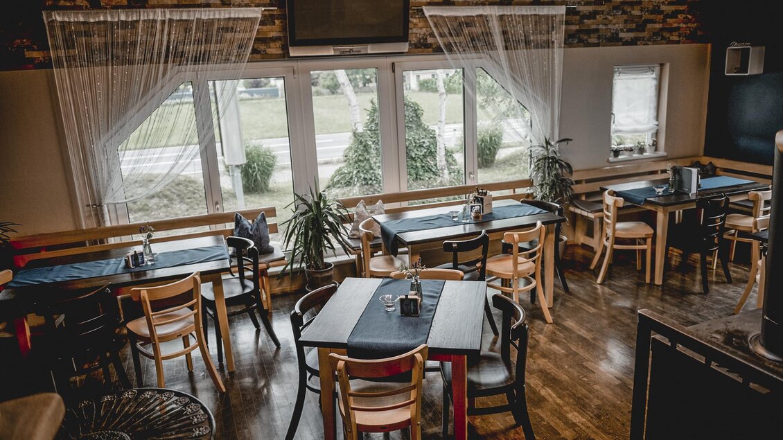 Ein gemütliches Restaurant mit Holzstühlen und Tischen. Große Fenster erlauben einen Blick ins Freie und sorgen für viel Tageslicht. | © Michaela Lorber