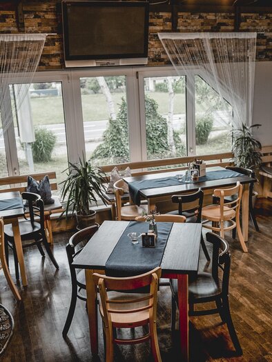 Ein gemütliches Restaurant mit Holzstühlen und Tischen. Große Fenster erlauben einen Blick ins Freie und sorgen für viel Tageslicht. | © Michaela Lorber