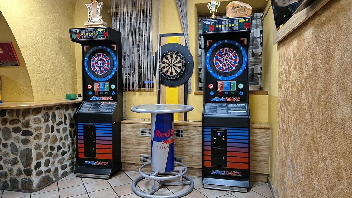 Zwei Spielautomaten und eine Dartscheibe stehen in einer gemütlichen Kneipe. Die Wände sind in gelb gestrichen, und der Boden besteht aus Fliesen. | © TV Murau