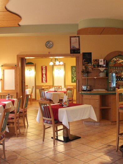 Ein gemütliches Restaurant mit mehreren Tischen und Stühlen. Die Wände sind warm gestaltet und es gibt eine kleine Bar im Hintergrund. | © Café Hotel Garni Thermenoase