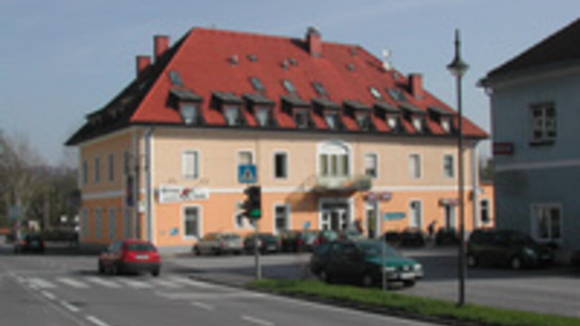 Ein pastelgelbes Gebäude mit rotem Dach steht an einer Straßenecke. Auf der Straße parken mehrere Autos. | © Tourismusverband Südsteiermark