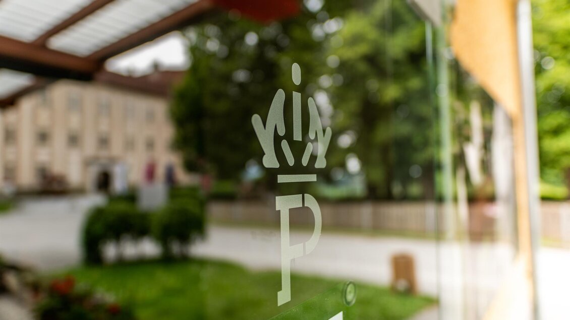 Blick durch Glasscheibe mit Logo auf Gastgarten des Café-Restaurant Piber mit Sitzplätzen und Gebäude im Hintergrund. | © Lipizzanerheimat_Die Abbilderei