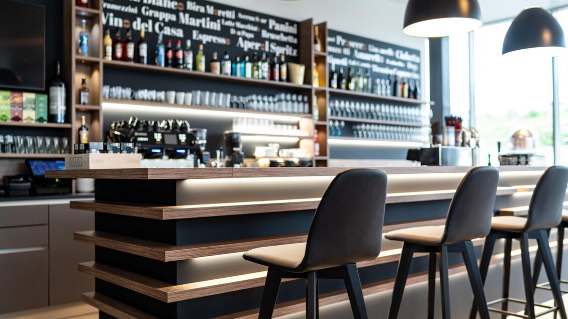 Moderne Bar mit Theke, Sitzplätzen und Getränkeregalen in der Café-Bar Verona in Voitsberg. | © Kalthuber photography
